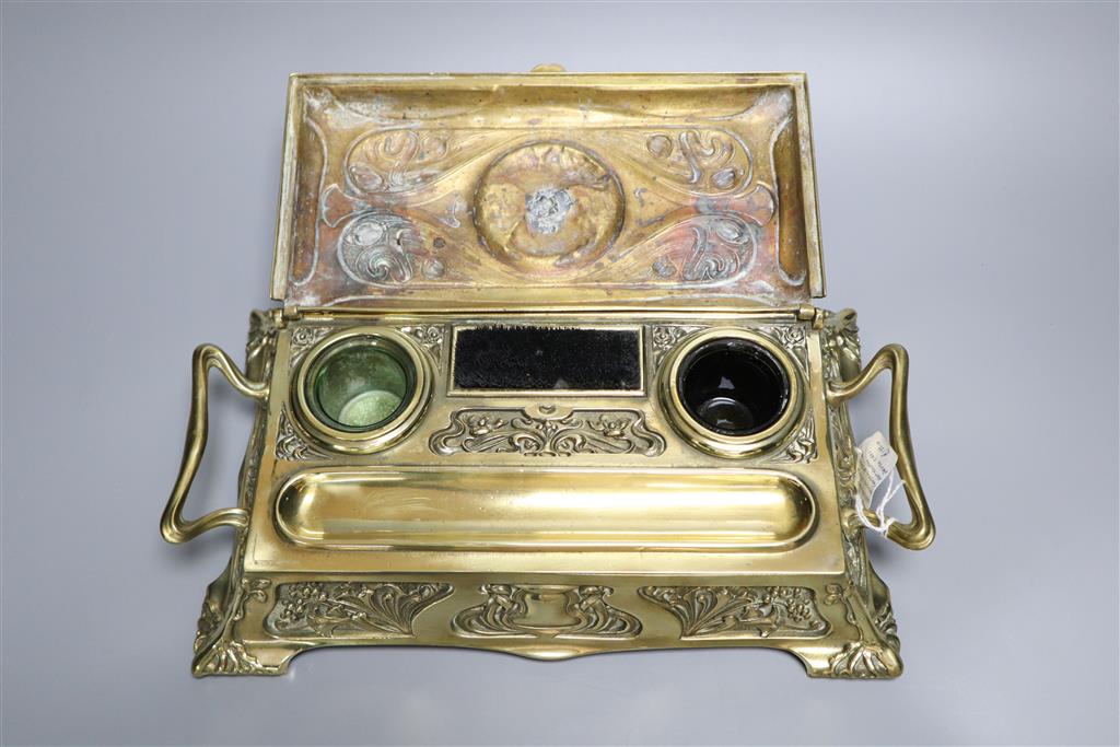 An Art Nouveau embossed brass desk stand including two bottle-green glass wells, 32cm